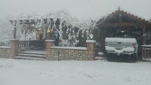Un edificio cubierto de nieve con entrada de piedra y un vehículo estacionado.