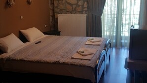 Un dormitorio con una cama grande, pared de piedra, radiador y televisor.