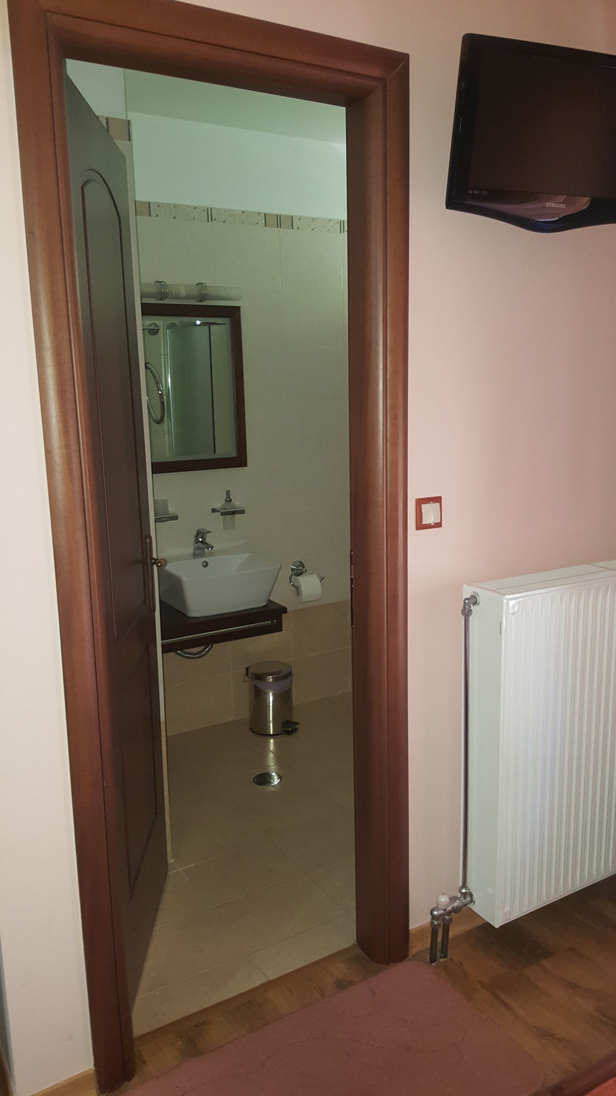 A bathroom with a sink, mirror, toilet, and radiator.