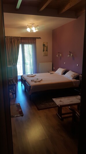 Un dormitorio con una cama grande, una mesita de noche, una silla, un radiador y una ventana con cortinas.