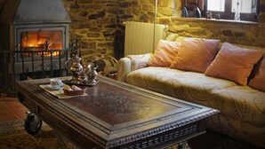 A cozy room with a stone wall, a fireplace, a sofa, and a table with tea set. - El Cajigal De Quintana (Espinosa de los Monteros)