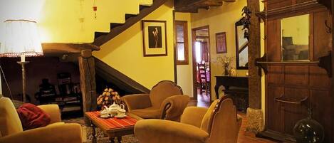 A cozy living room with a wooden staircase, comfortable seating, and a traditional wooden cabinet.