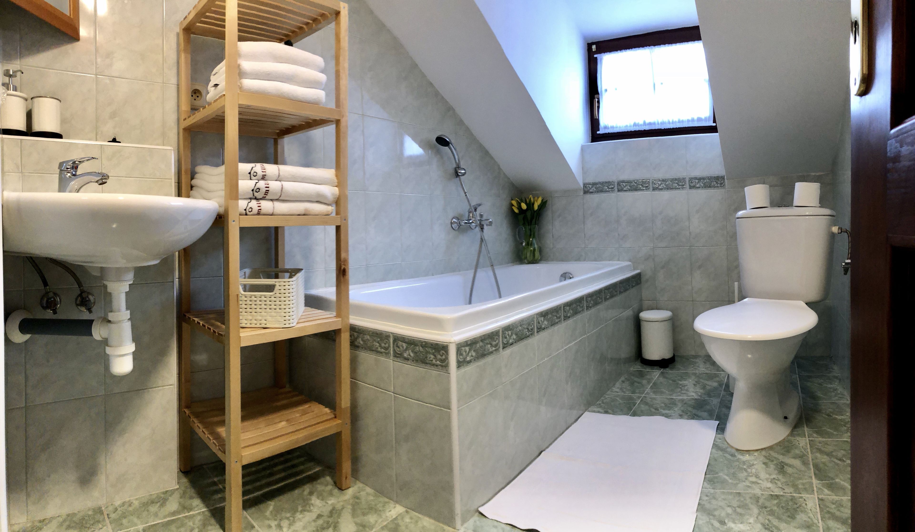 Ein Badezimmer mit Waschbecken, Toilette, Badewanne und Ablagefläche mit Handtüchern.
