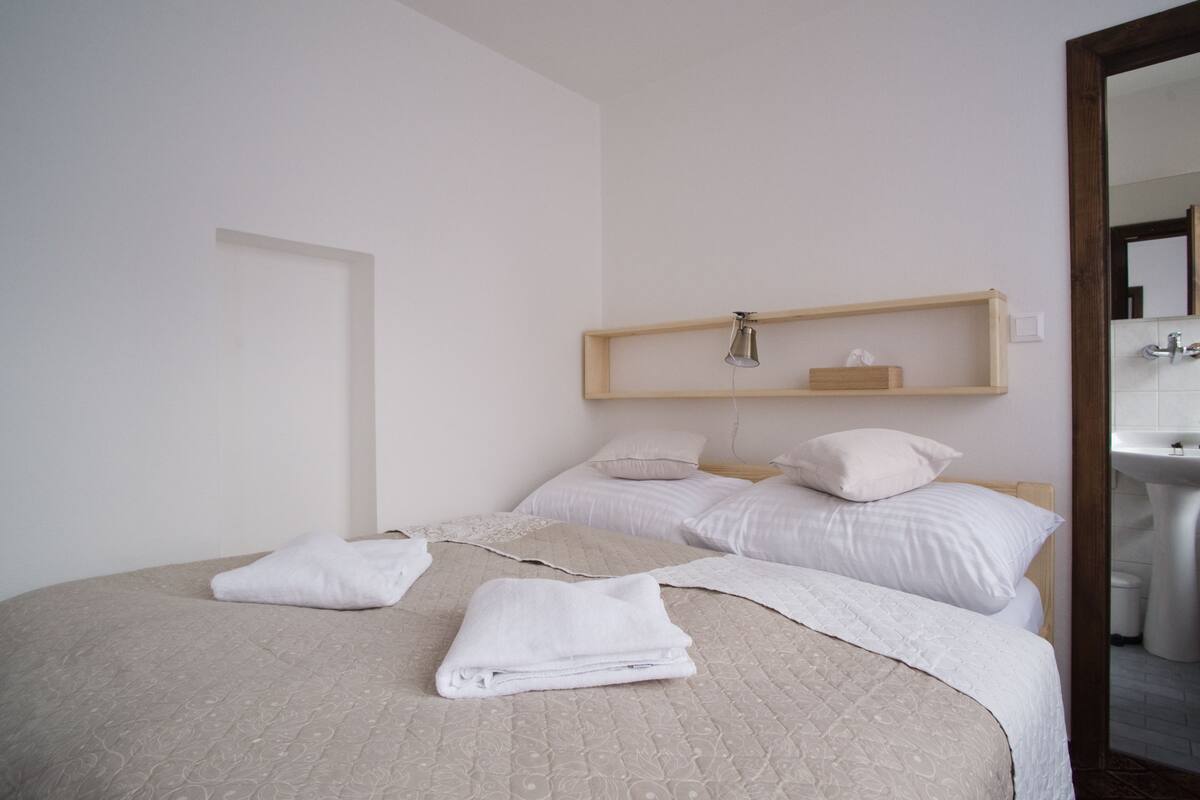 Ein Schlafzimmer mit einem Bett, Kissen, einem Nachttisch und einem Spiegel.
