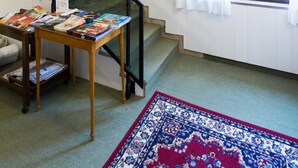 A staircase with a glass railing, a table with books, and a window with white curtains. - Krizman (Monrupino)
