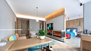 A modern living room with a wooden dining table, a sofa with colorful cushions, a large potted plant, and a TV mounted on the wall. - Mehood Lestie Hotel Panyu Branch (Guangzhou)