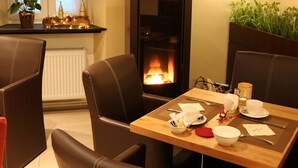 A cozy room with a fireplace, leather chairs, a dining table set with plates, cups, and cutlery.