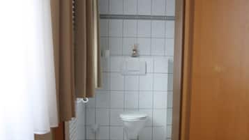 Un baño con inodoro, ducha y radiador.