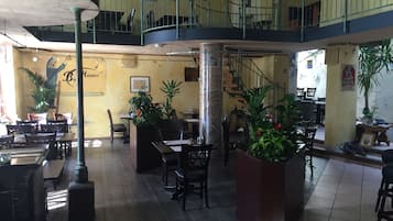 A multi-level restaurant with a central column, multiple dining tables, chairs, and potted plants.