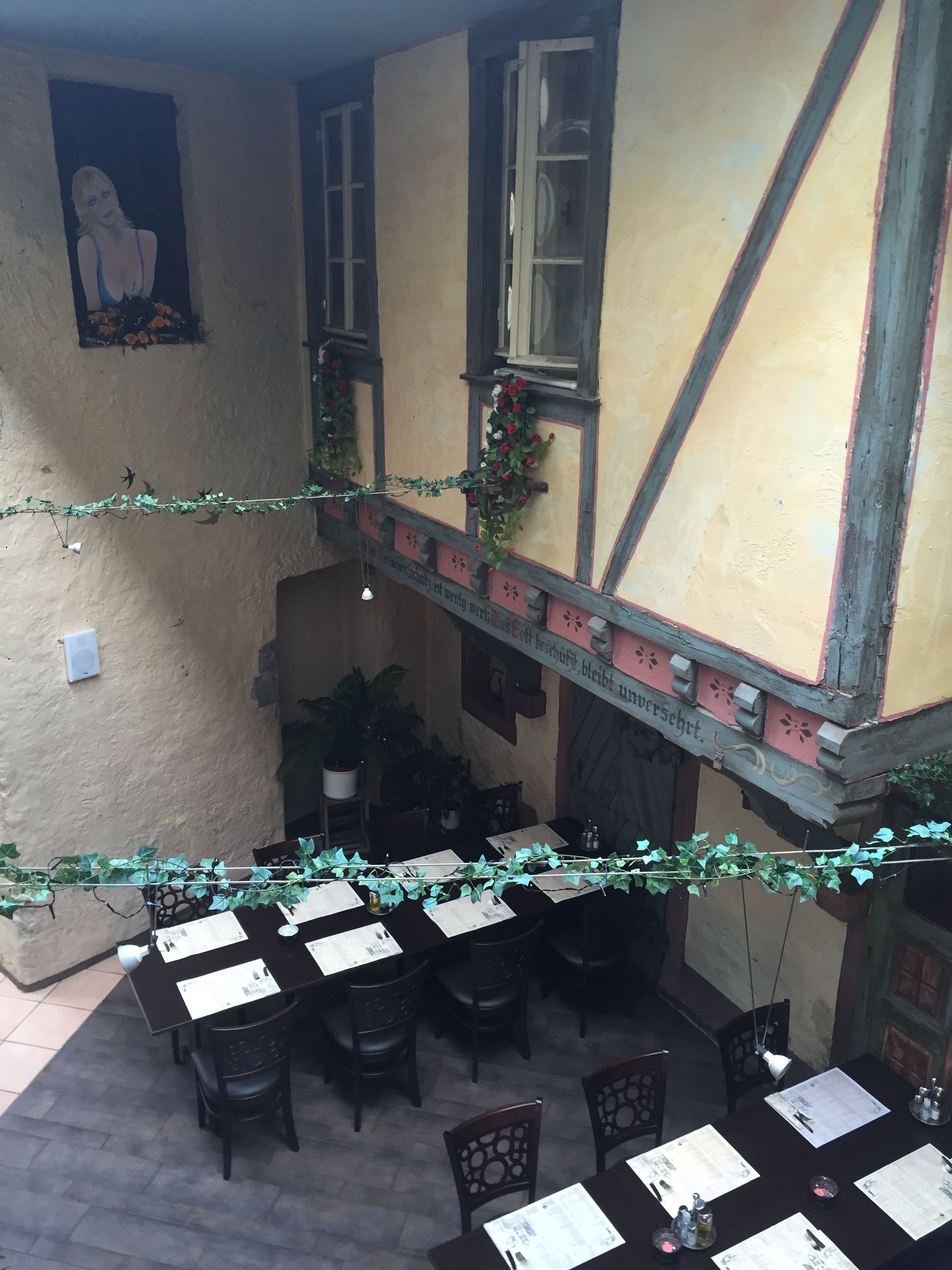 An indoor dining area with tables set for guests, a staircase, and a mural on the wall.