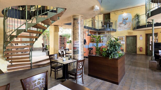 A spacious lobby with a central staircase, multiple seating areas, and a large planter with greenery. - Beim Heines (Daun)