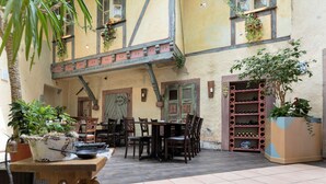 An outdoor dining area with wooden tables and chairs, a wine rack, and potted plants. - Beim Heines (Daun)