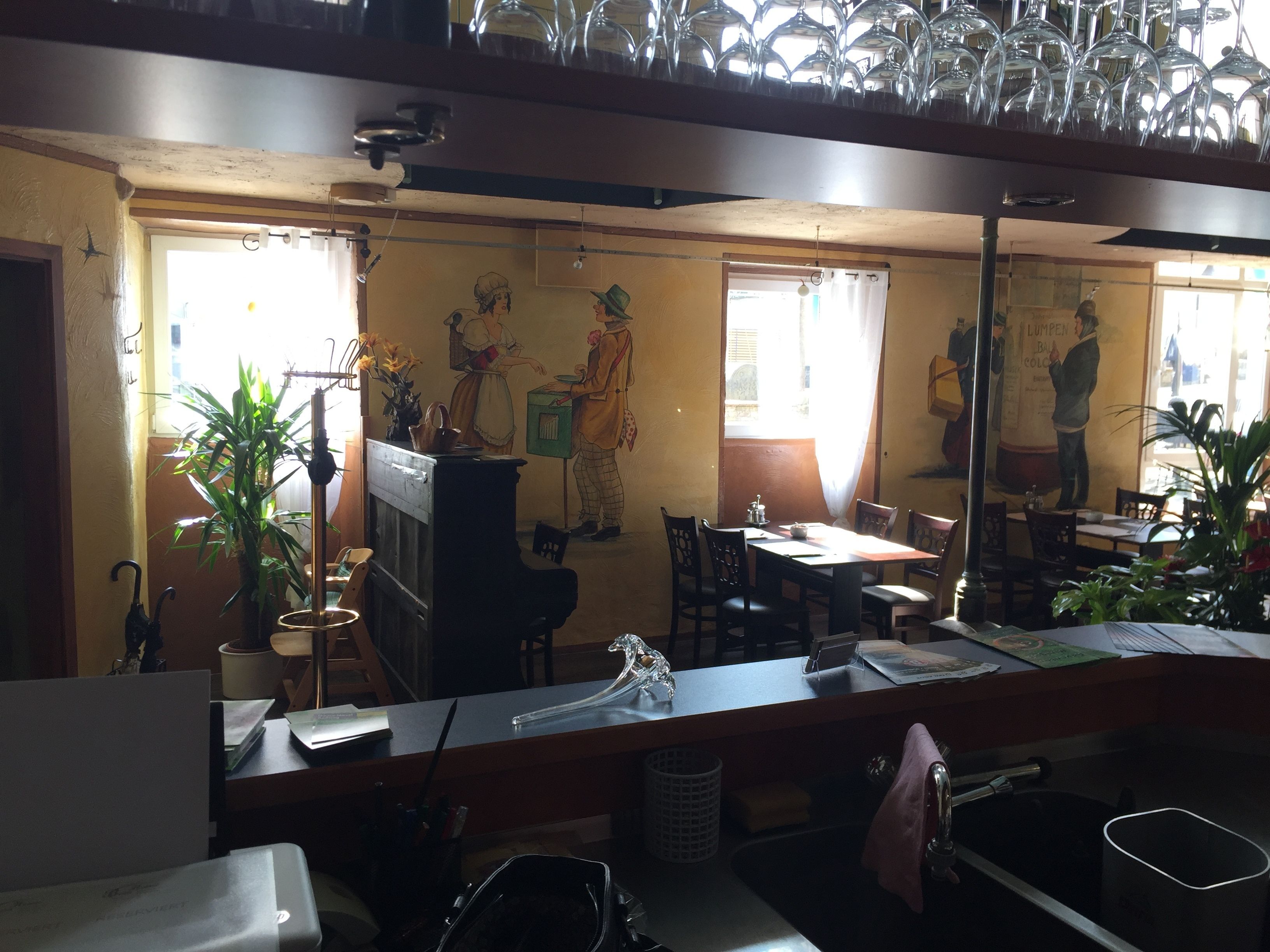 A restaurant with a long counter, multiple chairs, and a large mirror reflecting the interior.