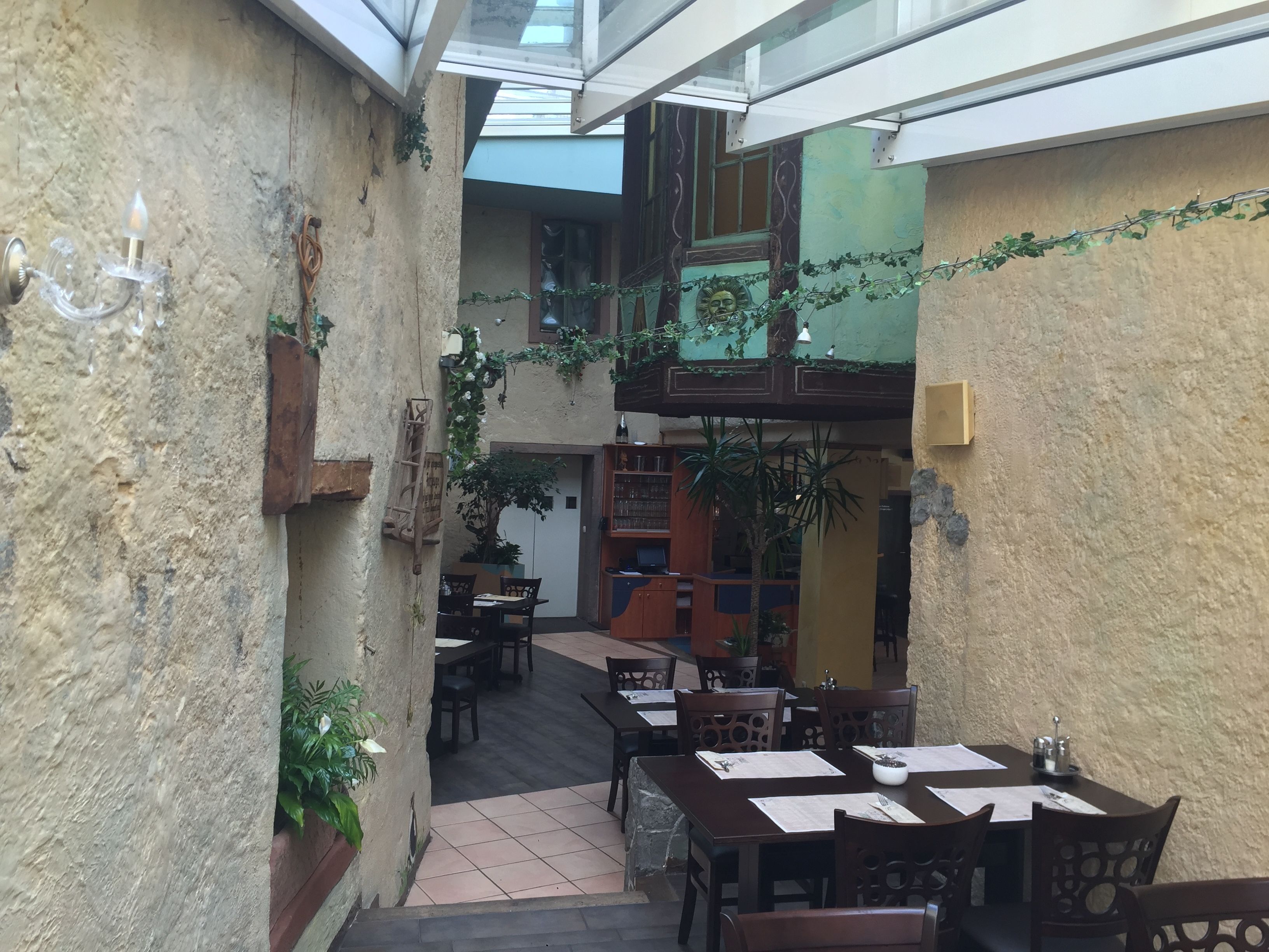 A narrow courtyard with outdoor seating, a staircase, and a view of the interior.