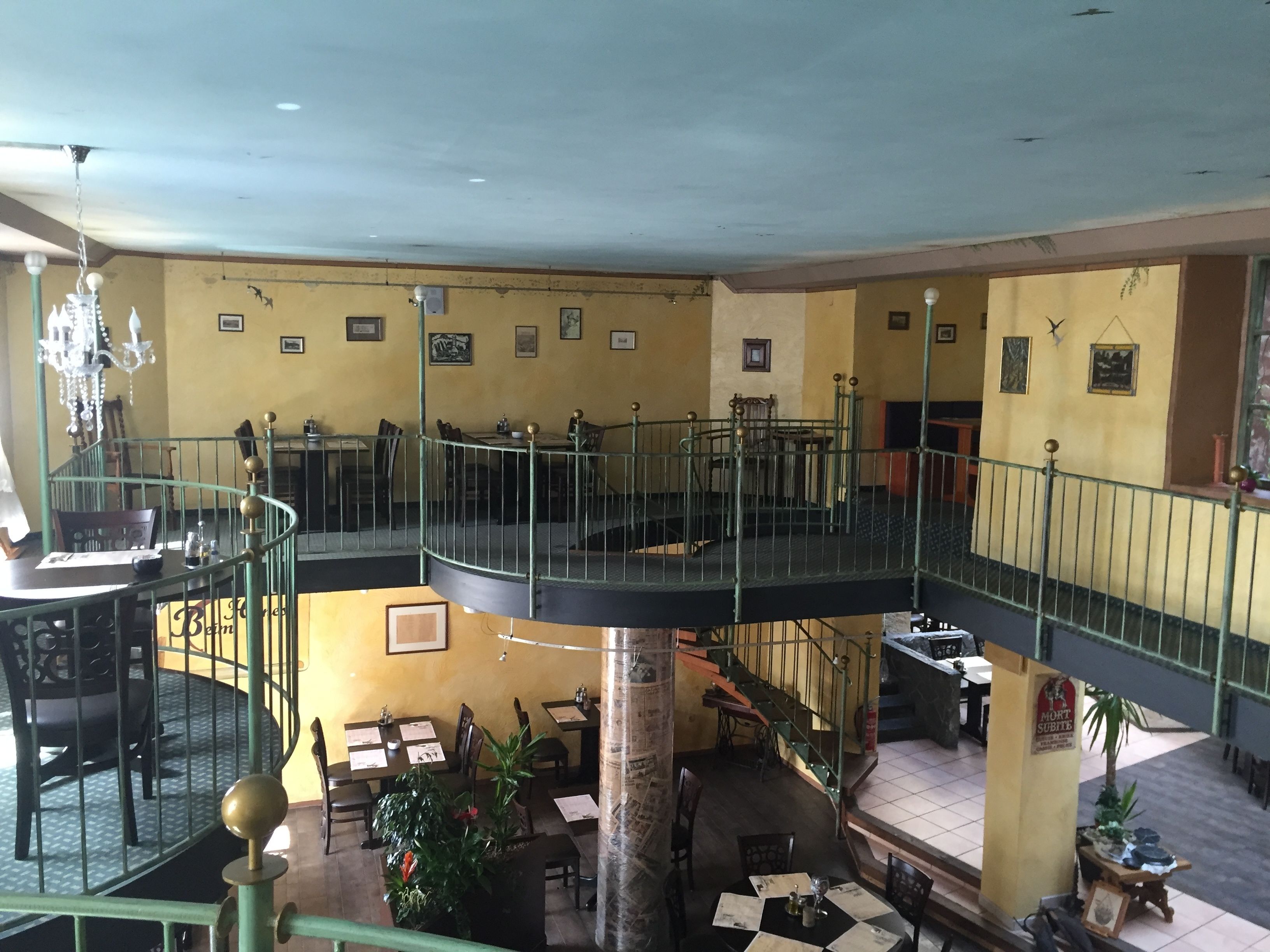Un ristorante su più livelli, con una scalinata centrale, tavoli, sedie e un lampadario.
