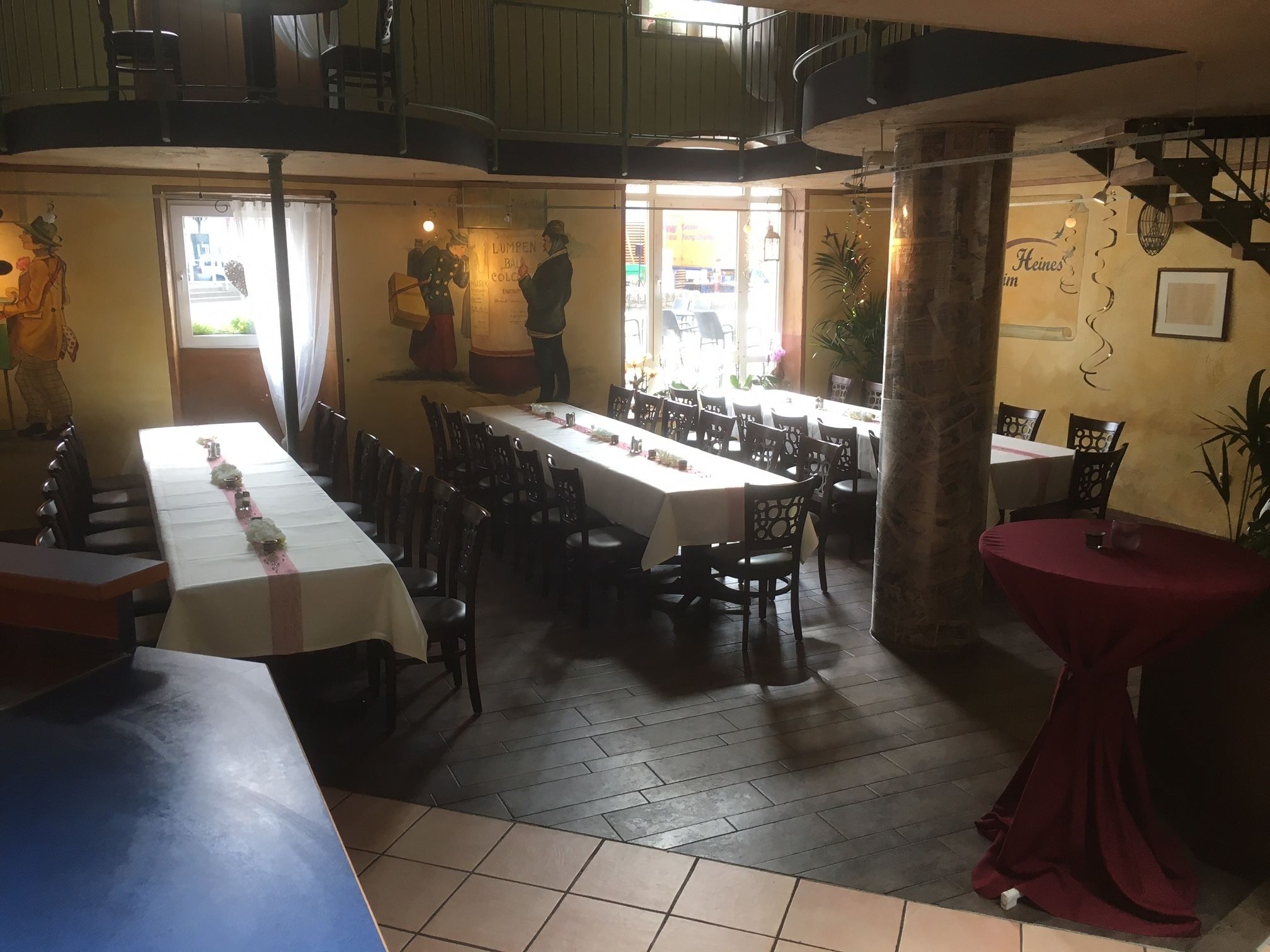 A restaurant with multiple dining tables, chairs, and a staircase.