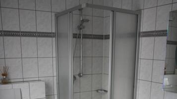 Un baño con ducha de vidrio, un inodoro y un lavabo con una toalla colgada en la pared.