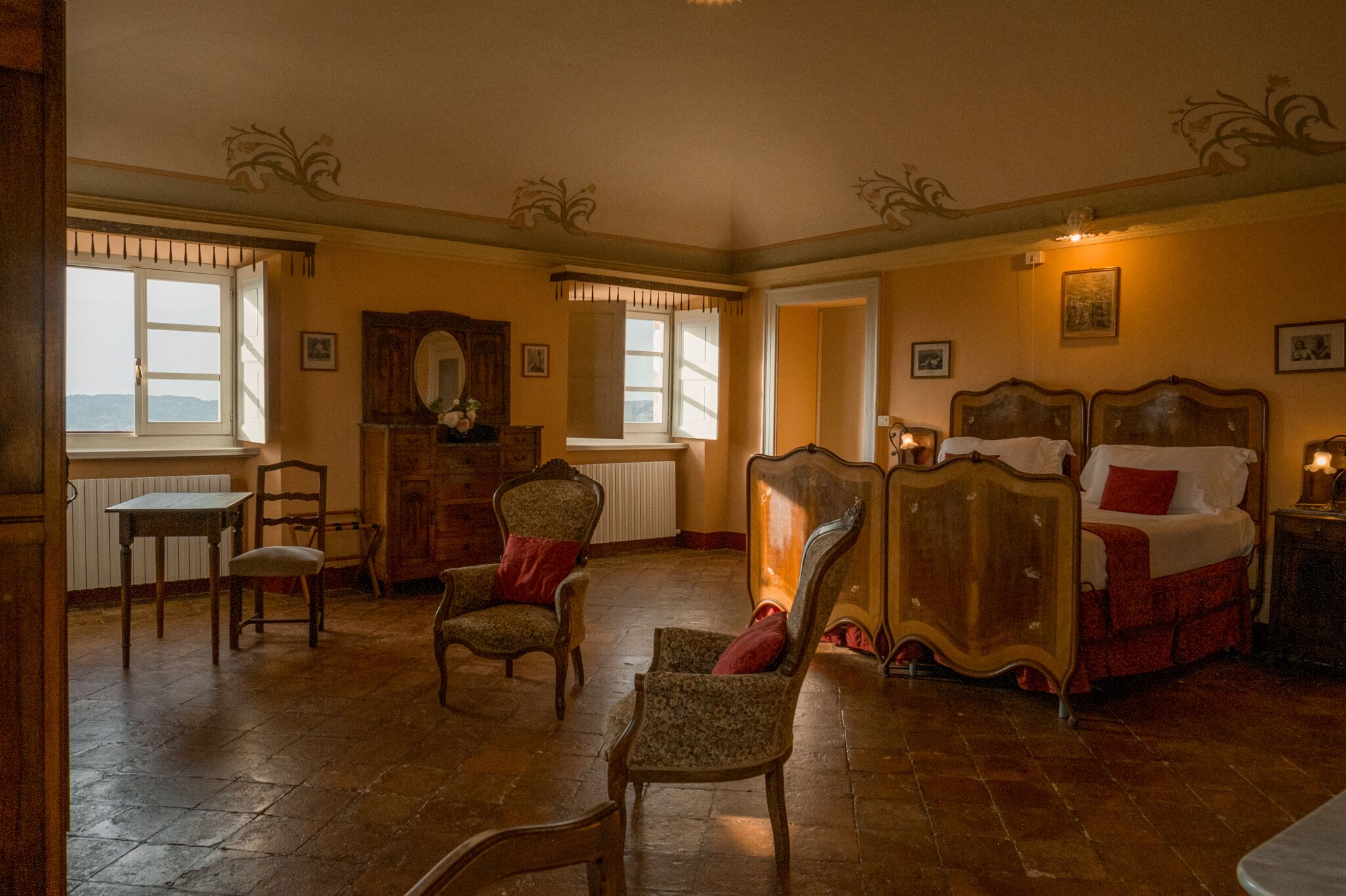 A room with a bed, two chairs, a table, and a dresser.