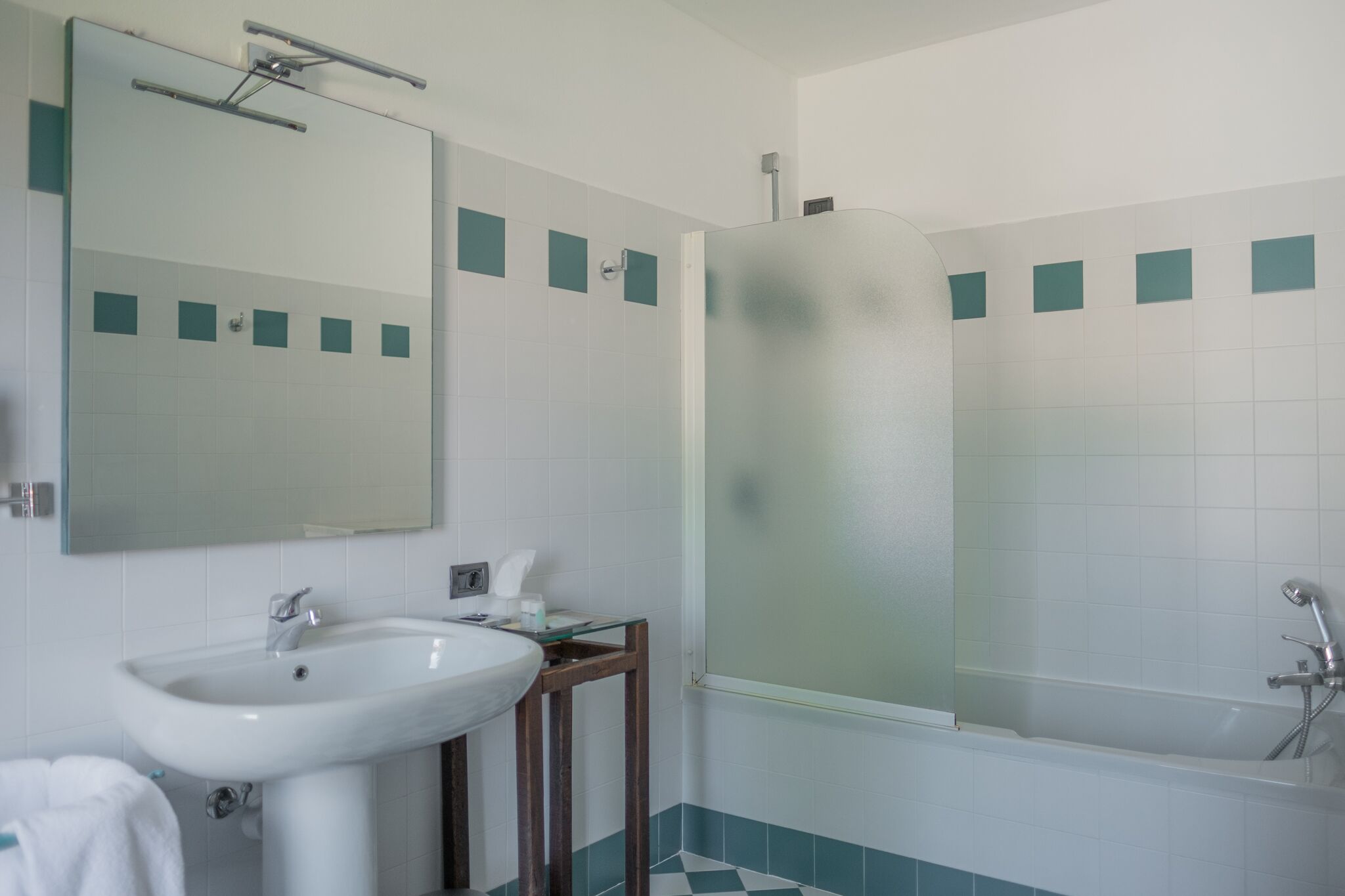 A bathroom with a sink, mirror, and frosted shower enclosure.