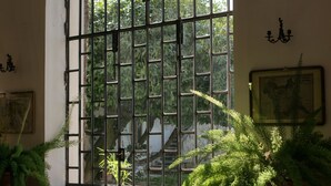 A room with a large arched window, a chandelier, and potted plants. - Albergo Real Castello (Verduno)