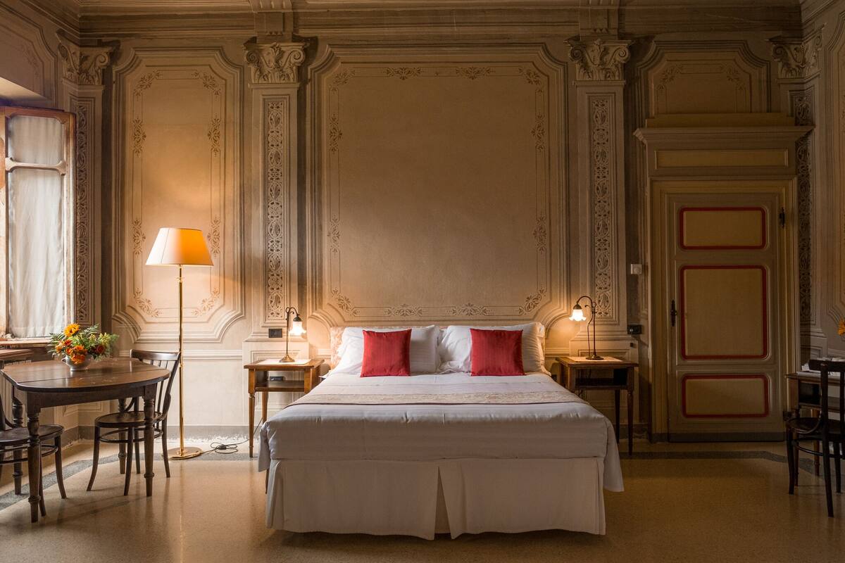 A hotel room with a large bed, two bedside tables, a desk, and a chair.