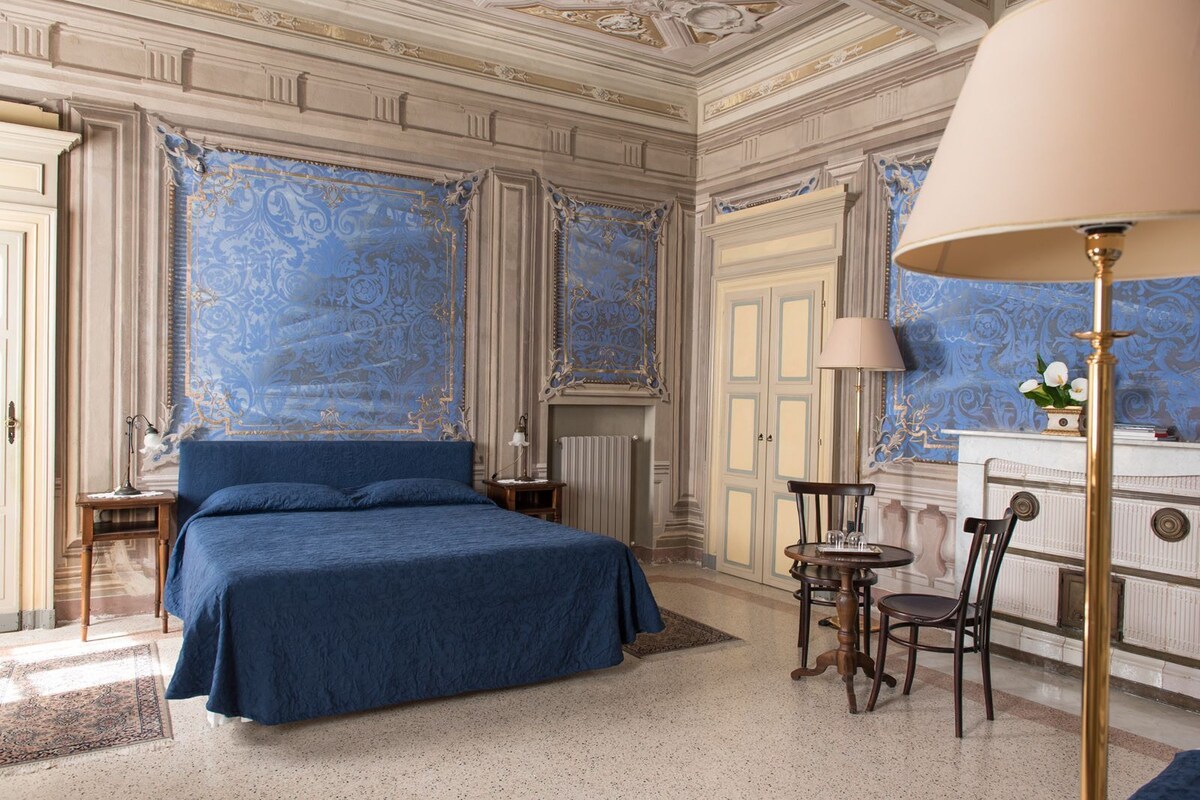 Una habitación con una cama grande, un escritorio, una silla, una lámpara y un aparador.