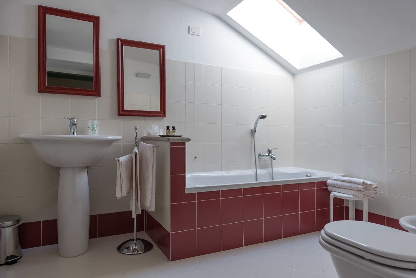 A bathroom with a skylight, a sink, a bathtub, and a toilet.