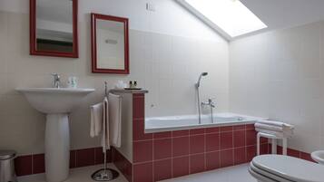A bathroom with a skylight, a sink, a bathtub, and a toilet.