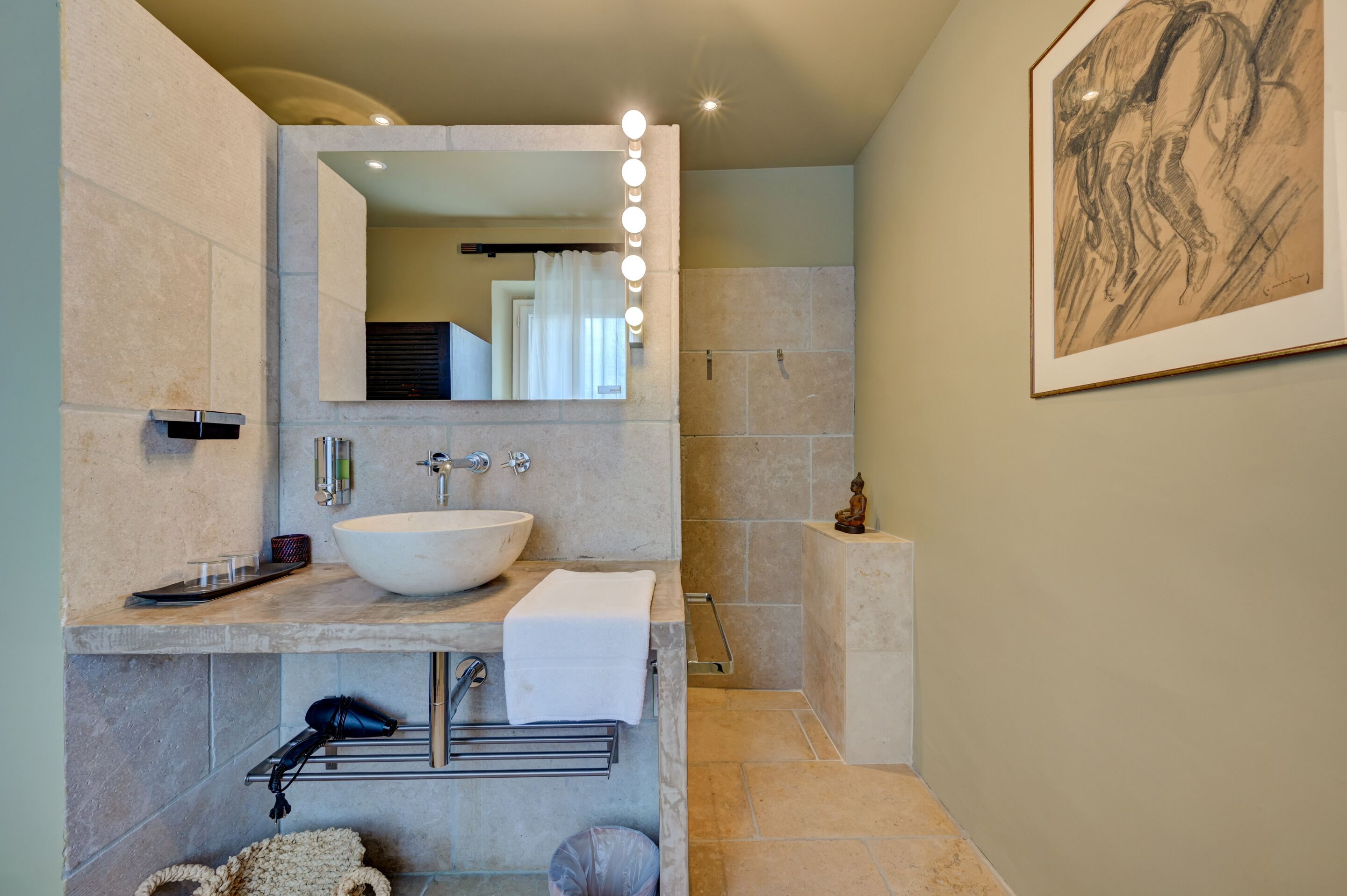 Une salle de bain moderne avec un grand miroir, un meuble-lavabo et un espace douche.
