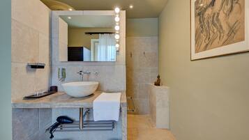 Une salle de bain moderne avec un grand miroir, un meuble-lavabo et un espace douche.