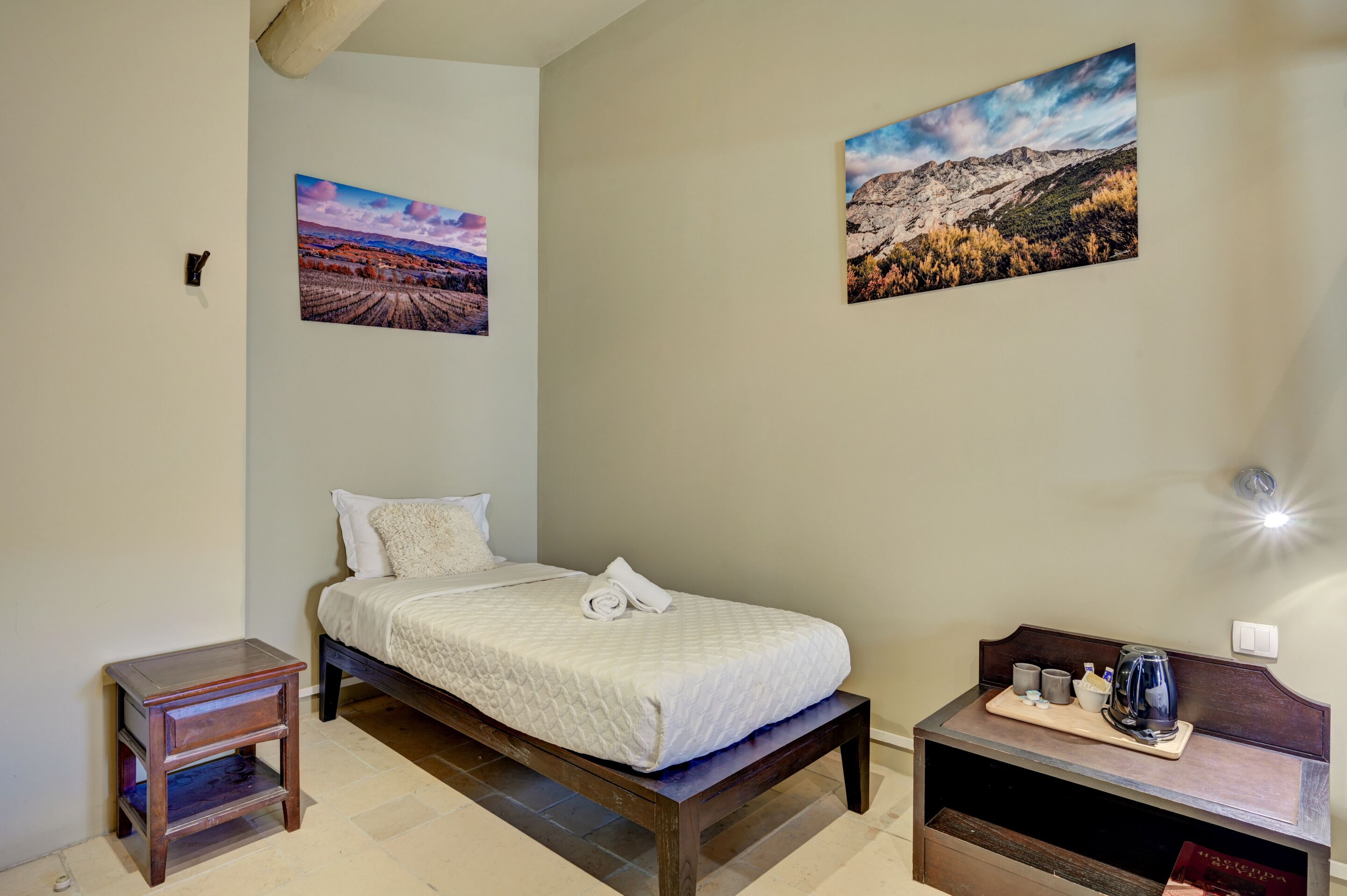 Quarto bem arrumado com cama, mesas de cabeceira e criado-mudo.