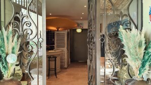 Une porte ornée de motifs en fer forgé, un tapis et des plantes en pot.