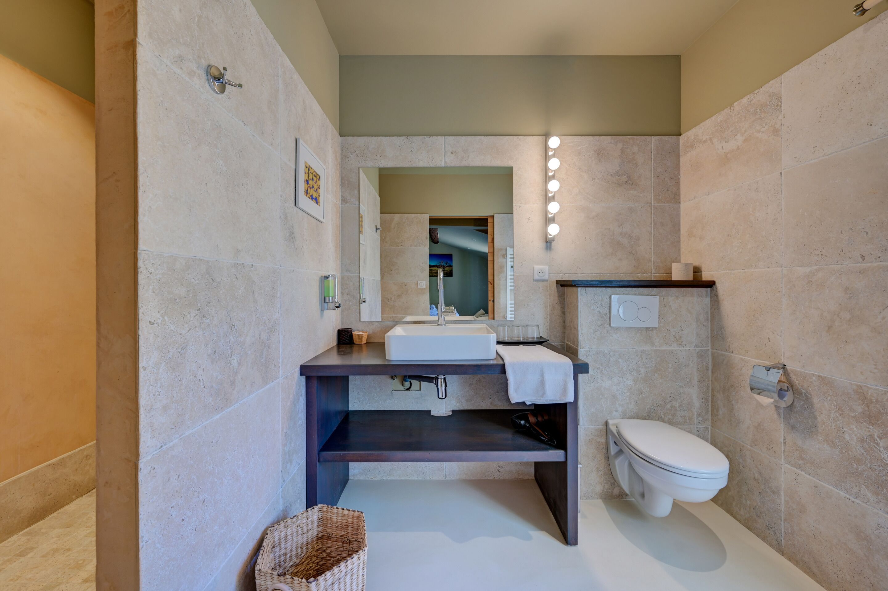Un bagno moderno con un lavandino bianco, un piano di appoggio scuro e un water.