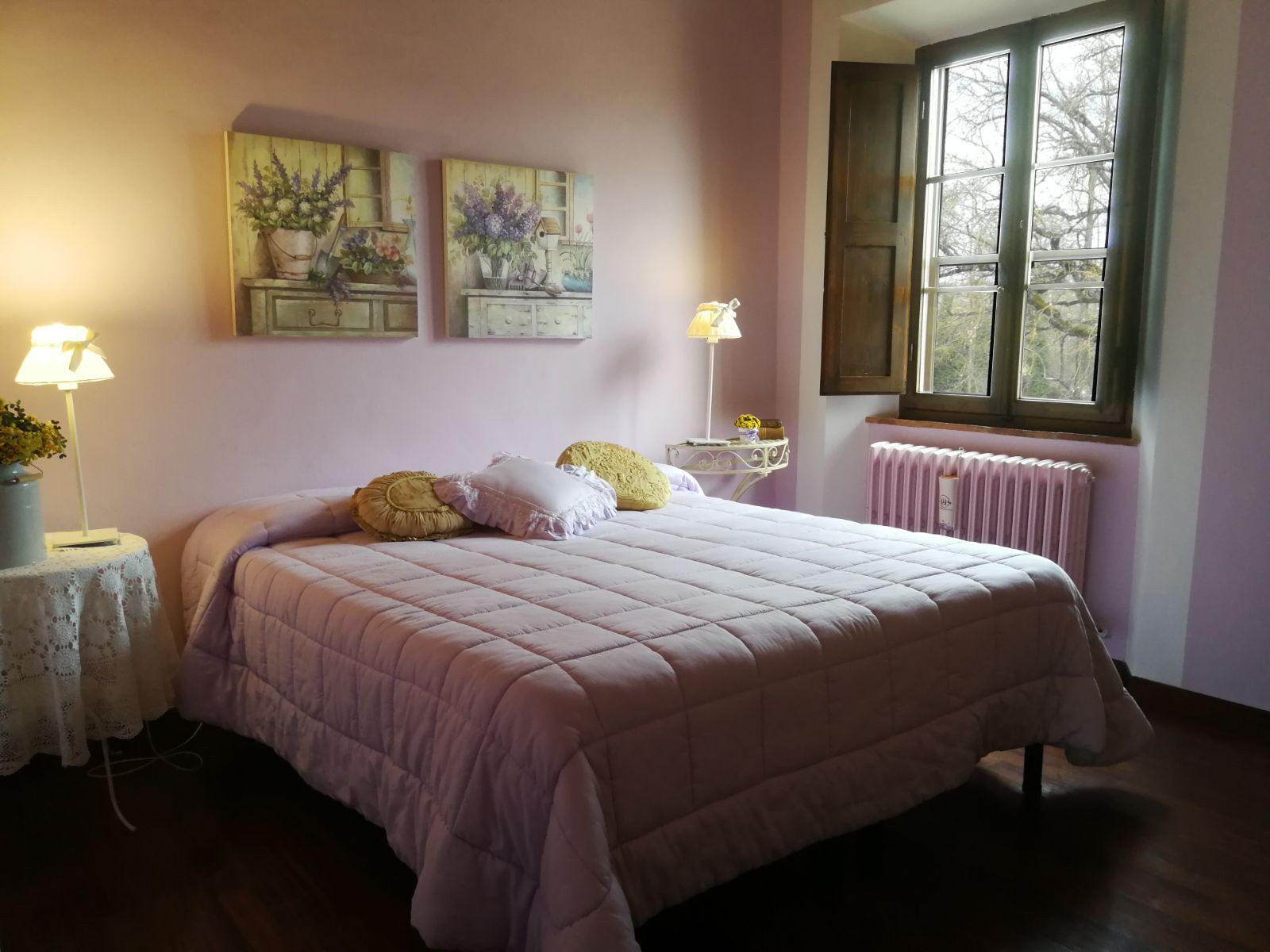 Ein Schlafzimmer mit einem Bett, zwei Nachttischen, einem Fenster und Wandbildern.