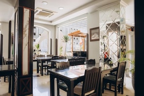 Un comedor con mesa de vidrio y sillas, rodeado de paredes con paneles decorativos y un ventanal que ofrece vistas de la ciudad.