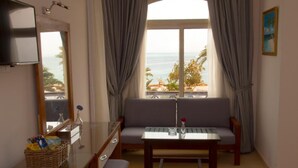 A room with a sofa, a small table, a TV, and a window with curtains. -  Fantasia Hotel (Hurghada)