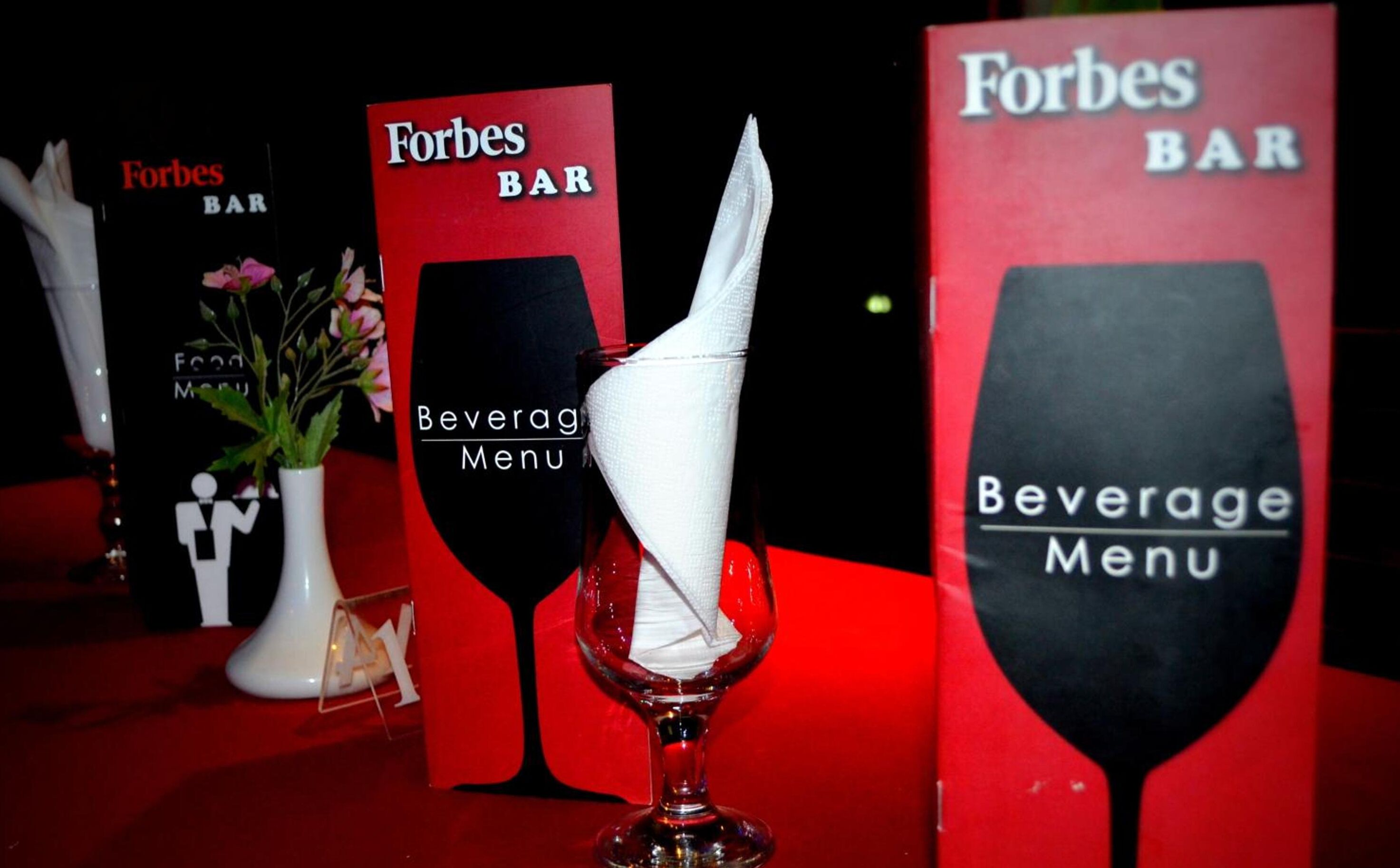 A Forbes Bar with a beverage menu displayed on a wine glass.
