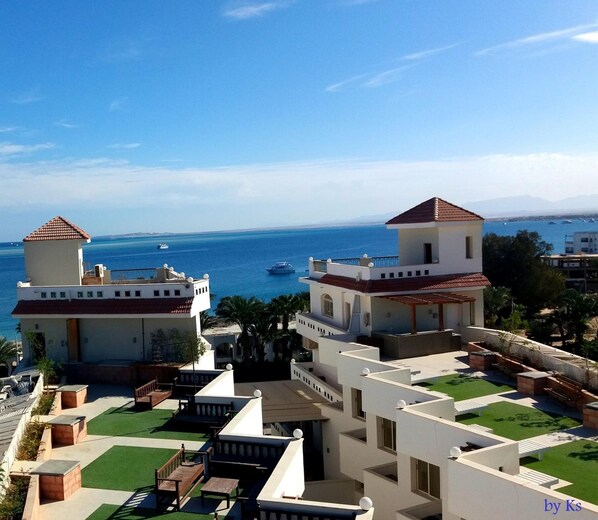 A coastal residential area with modern buildings, a clear view of the sea, and a well-maintained green space. -  Fantasia Hotel (Hurghada)
