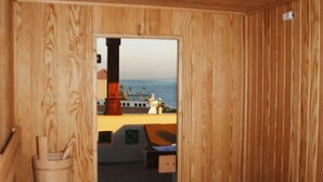 A wooden sauna room with a bench and a small table. -  Fantasia Hotel (Hurghada)