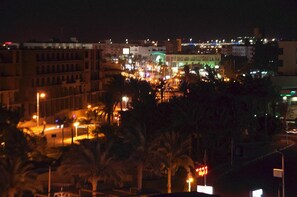 Un paisaje urbano nocturno con edificios iluminados y palmeras.