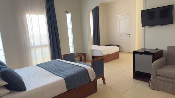A hotel room with two beds, a TV, a desk, and a chair. -  Fantasia Hotel (Hurghada)