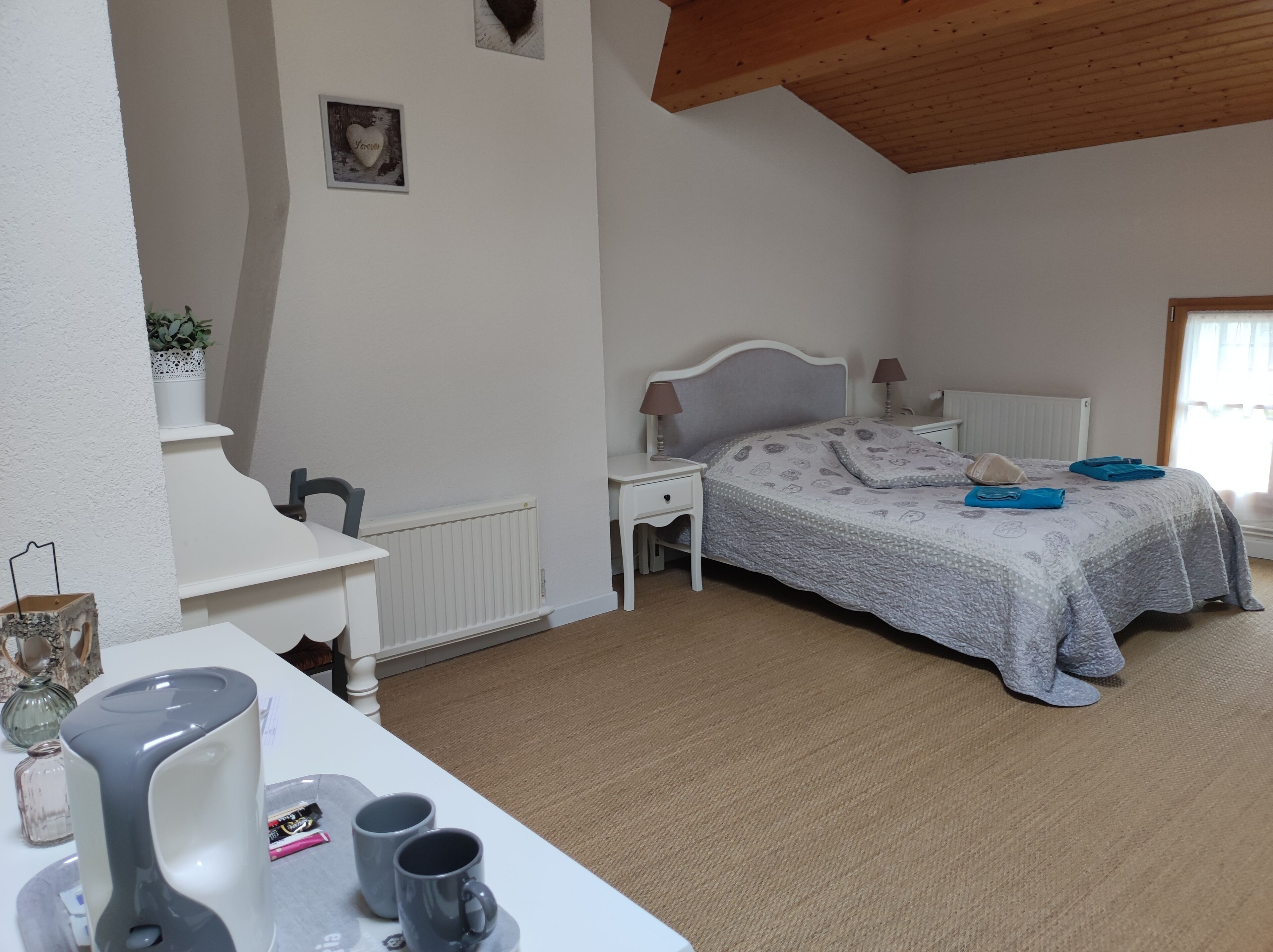 A bedroom with a bed, bedside tables, a desk, and a radiator.