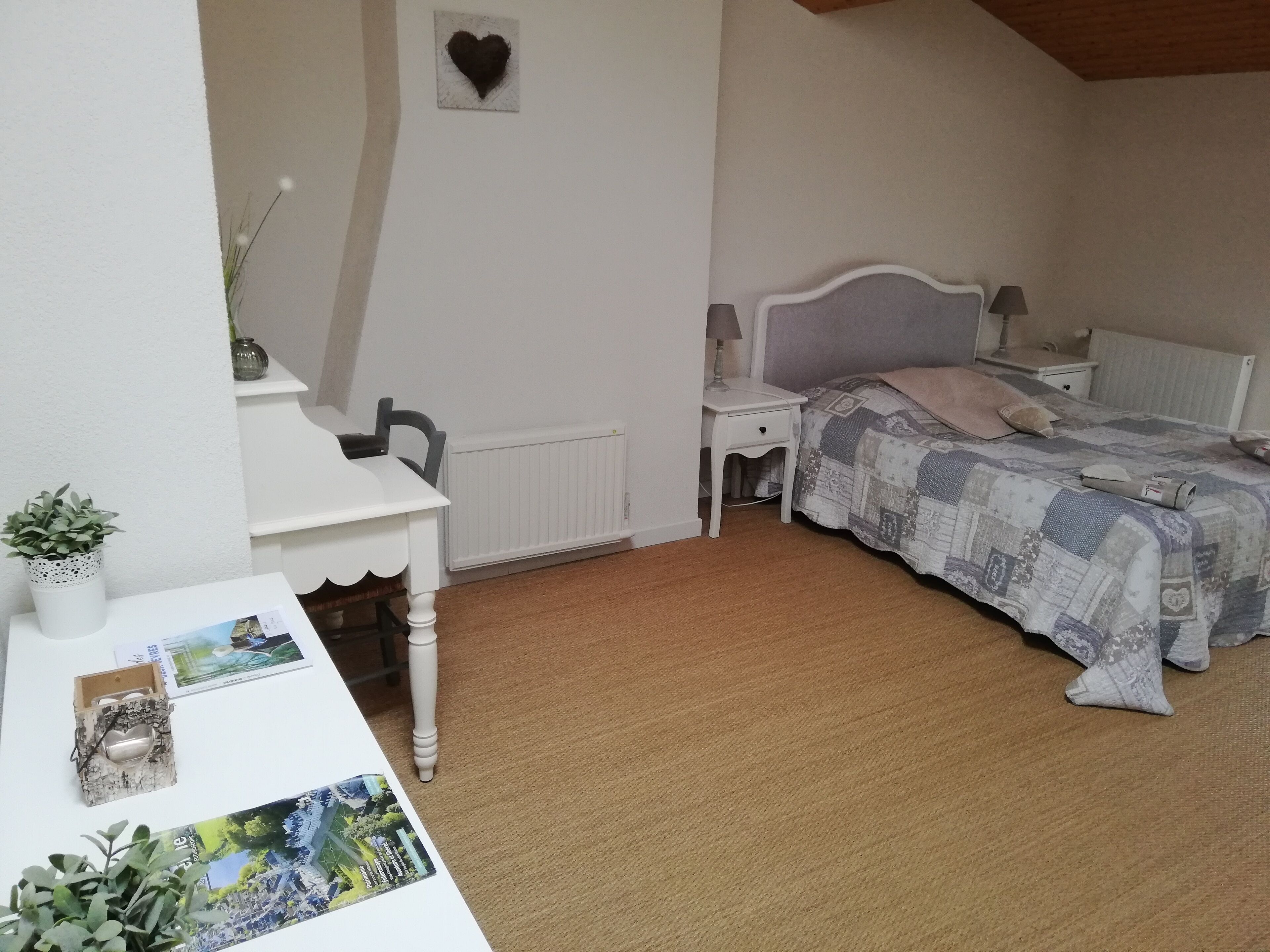 Un dormitorio con cama, mesitas de noche, un escritorio y un radiador.