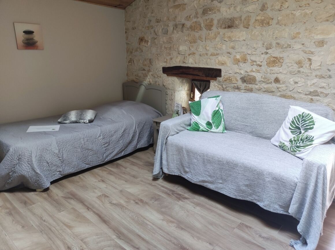 A room with two beds, a stone wall, and a wooden floor.