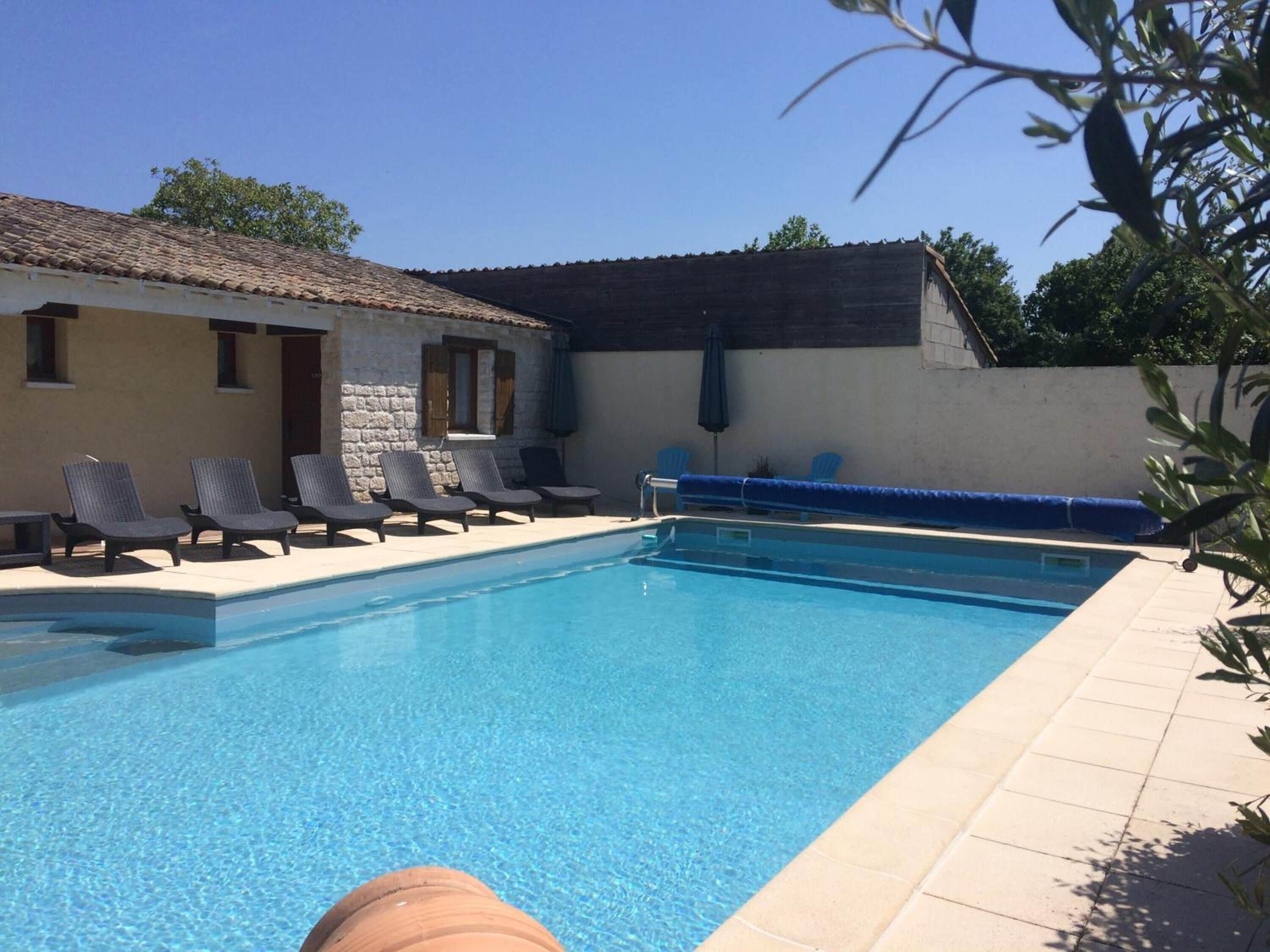 A swimming pool with lounge chairs and a stone building in the background.