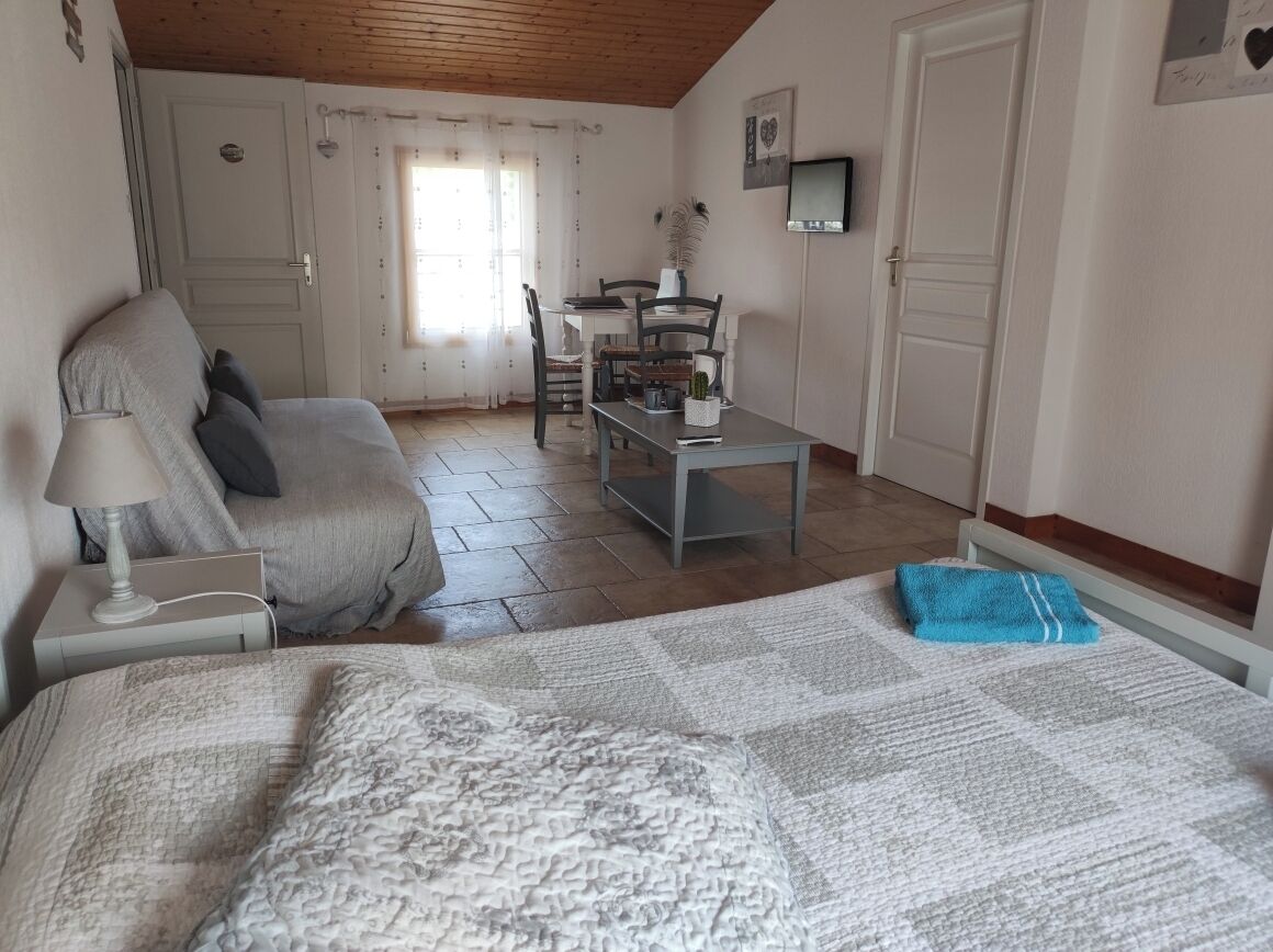 Une chambre à coucher comprenant un lit, une table de chevet, une lampe et donnant sur un coin repas avec des chaises et une table.