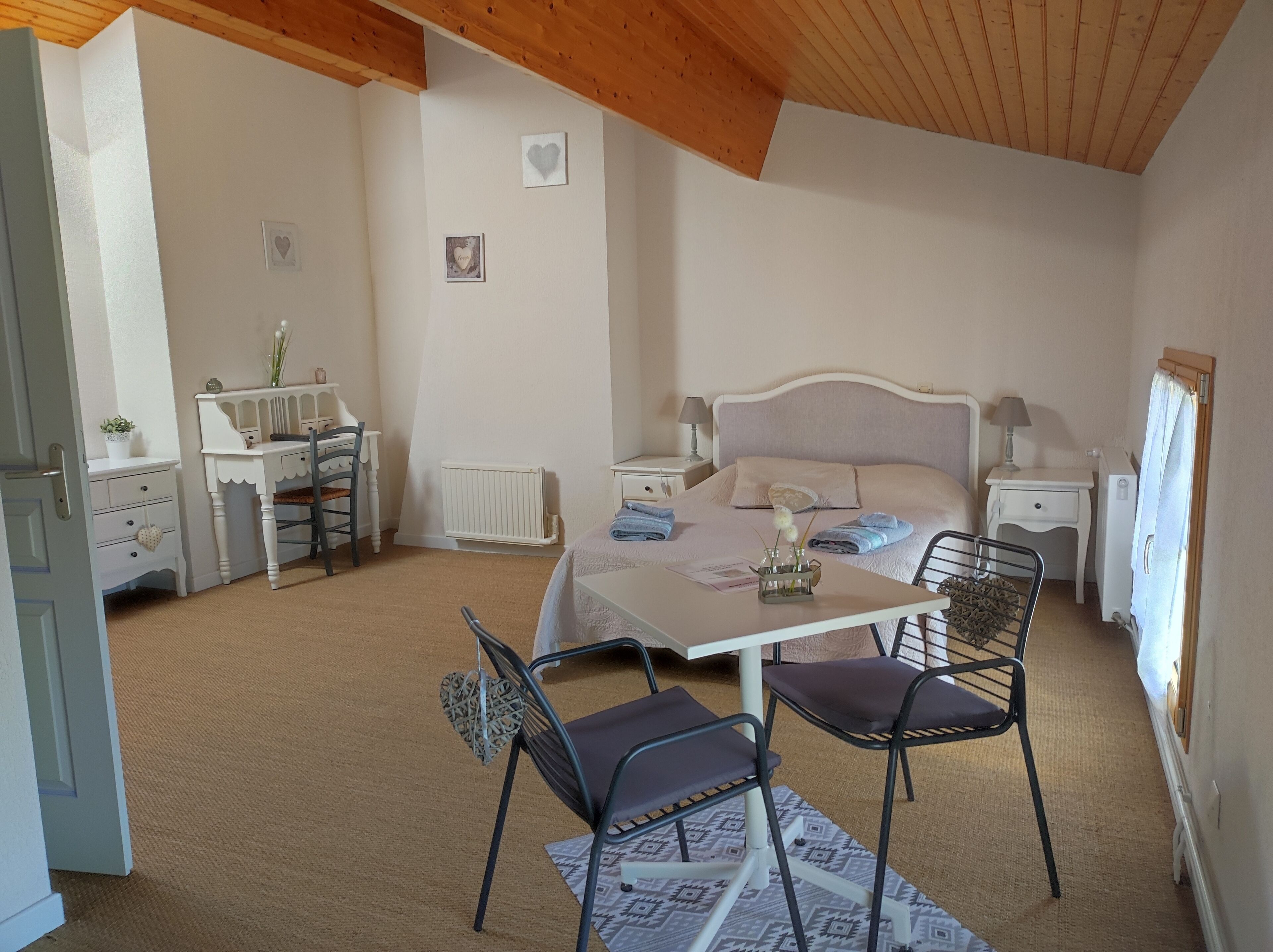 A bedroom with a bed, bedside tables, a desk, chairs, and a radiator.
