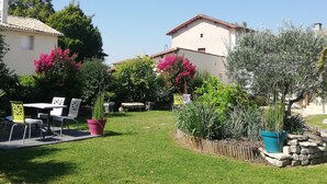 A courtyard with a table and chairs, surrounded by potted plants and a stone wall. - Les Chenêts (Chenay)