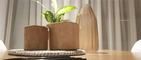 Una mesa de madera con dos plantas en macetas, un bolígrafo y un cuaderno.