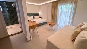 Una habitación de hotel moderna con una cama, un escritorio de madera, un taburete pequeño y un ventanal con cortinas.